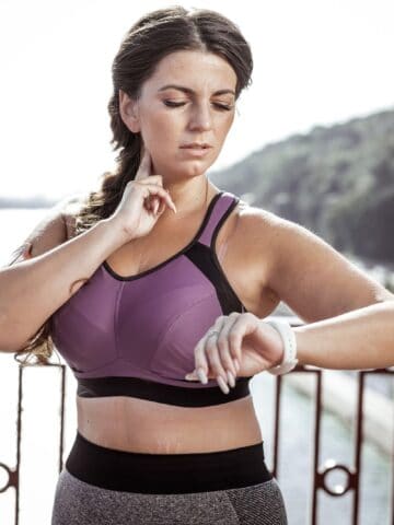 A woman taking her pulse at her neck to check her heart rate.