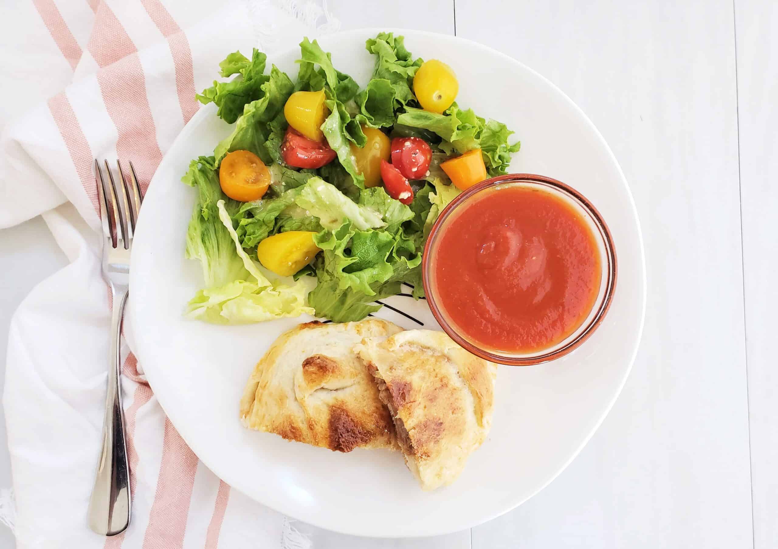 Pizza pockets with dipping sauce and salad on the side.