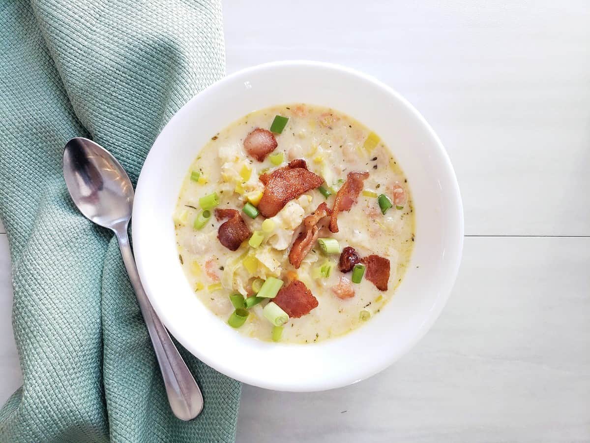 Cauliflower chowder in a bowl garnished with bacon and green onions.