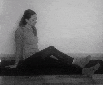 A woman doing a long sitting glute stretch.