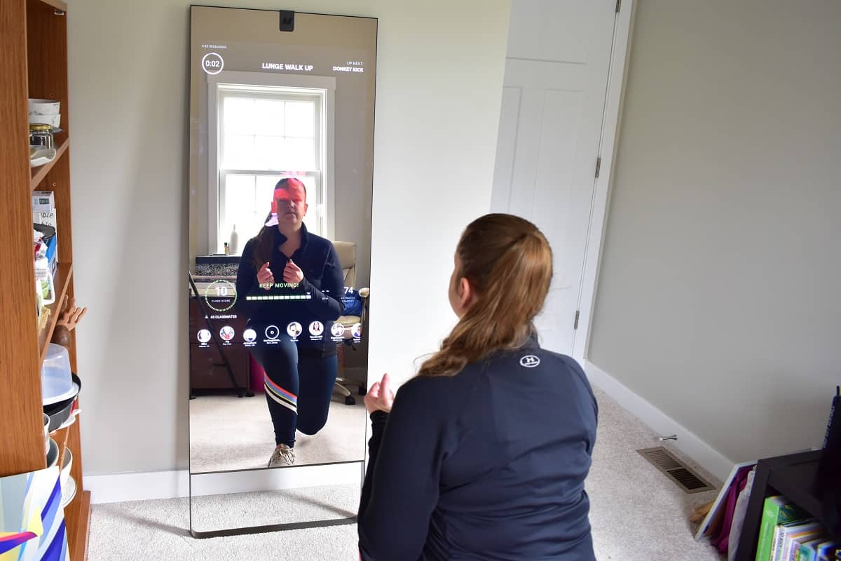 A woman doing a reverse lunge in front of the lululemon studio mirror.