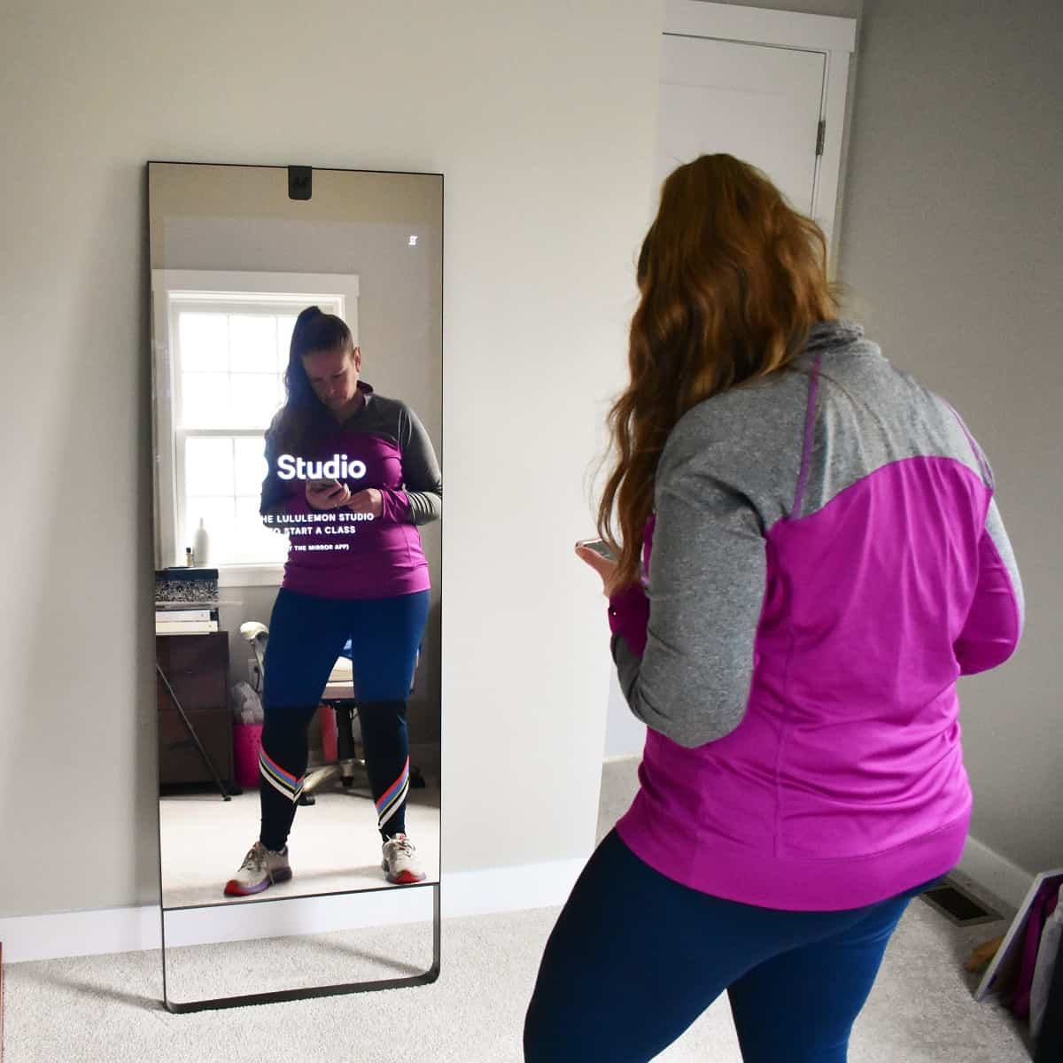 A woman looking at her phone to select an exercise class.