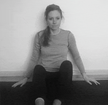 A woman doing a seated forward lean to stretch her hips and glutes.