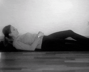 A woman doing a supine figure four stretch.