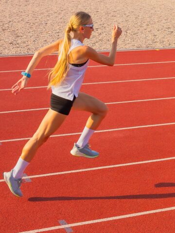 A woman in shorts sprinting on a track for running intervals.