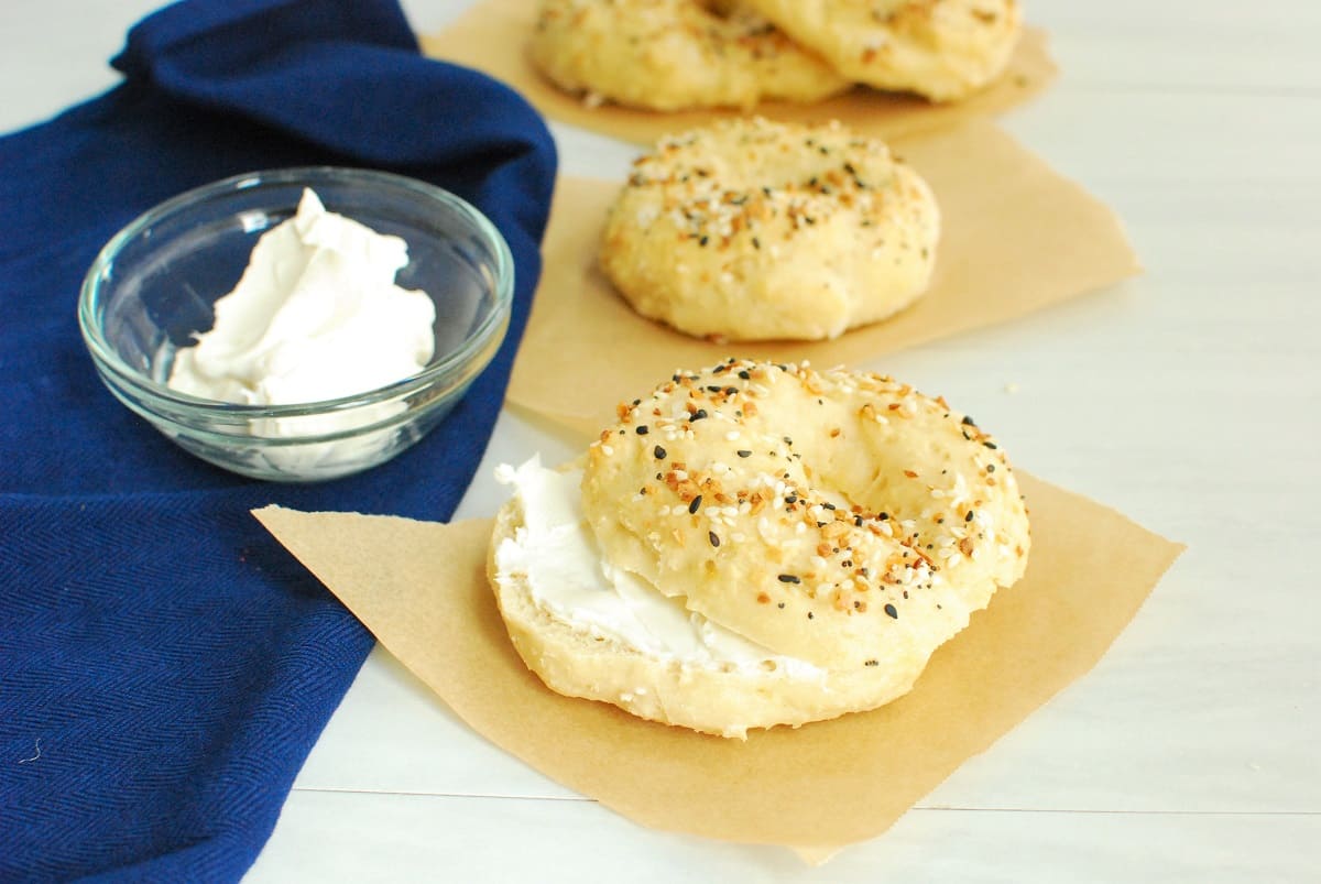 A cottage cheese bagel with cream cheese on a piece of parchment paper.