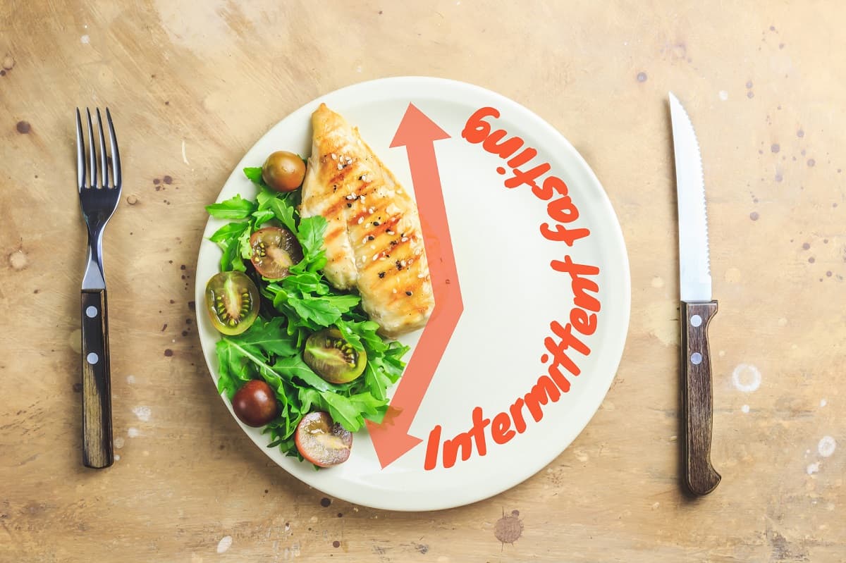 Chicken and salad on part of a plate, with the other part empty and labeled intermittent fasting.