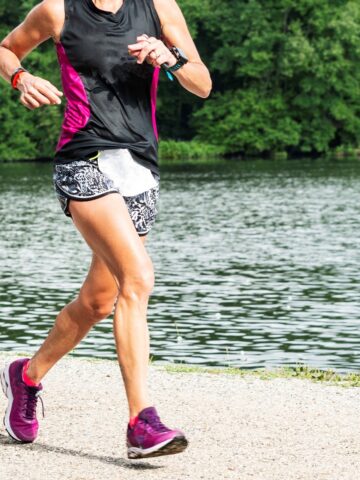 A woman hoping to achieve a good 5K time in the race she's running along a lake waterfront.