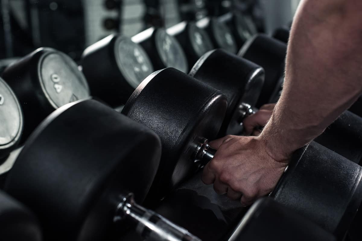 A man grabbing dumbbells at a gym.