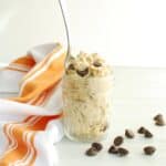 A small mason jar filled with cottage cheese cookie dough, with a spoon stuck into it.