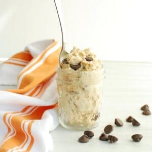 A small mason jar filled with cottage cheese cookie dough, with a spoon stuck into it.