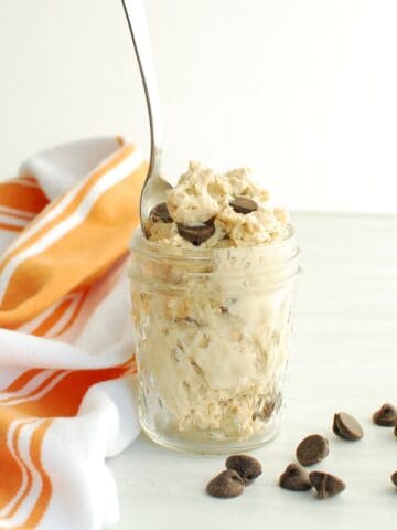 A small mason jar filled with cottage cheese cookie dough, with a spoon stuck into it.