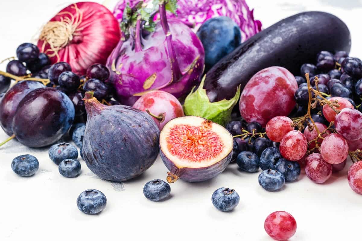 A selection of foods with anthocyanins like blueberries, red cabbage, and grapes.