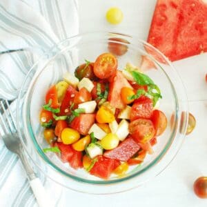An overhead shot of a glass bowl filled with watermelon caprese salad.