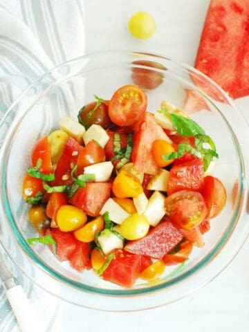 An overhead shot of a glass bowl filled with watermelon caprese salad.