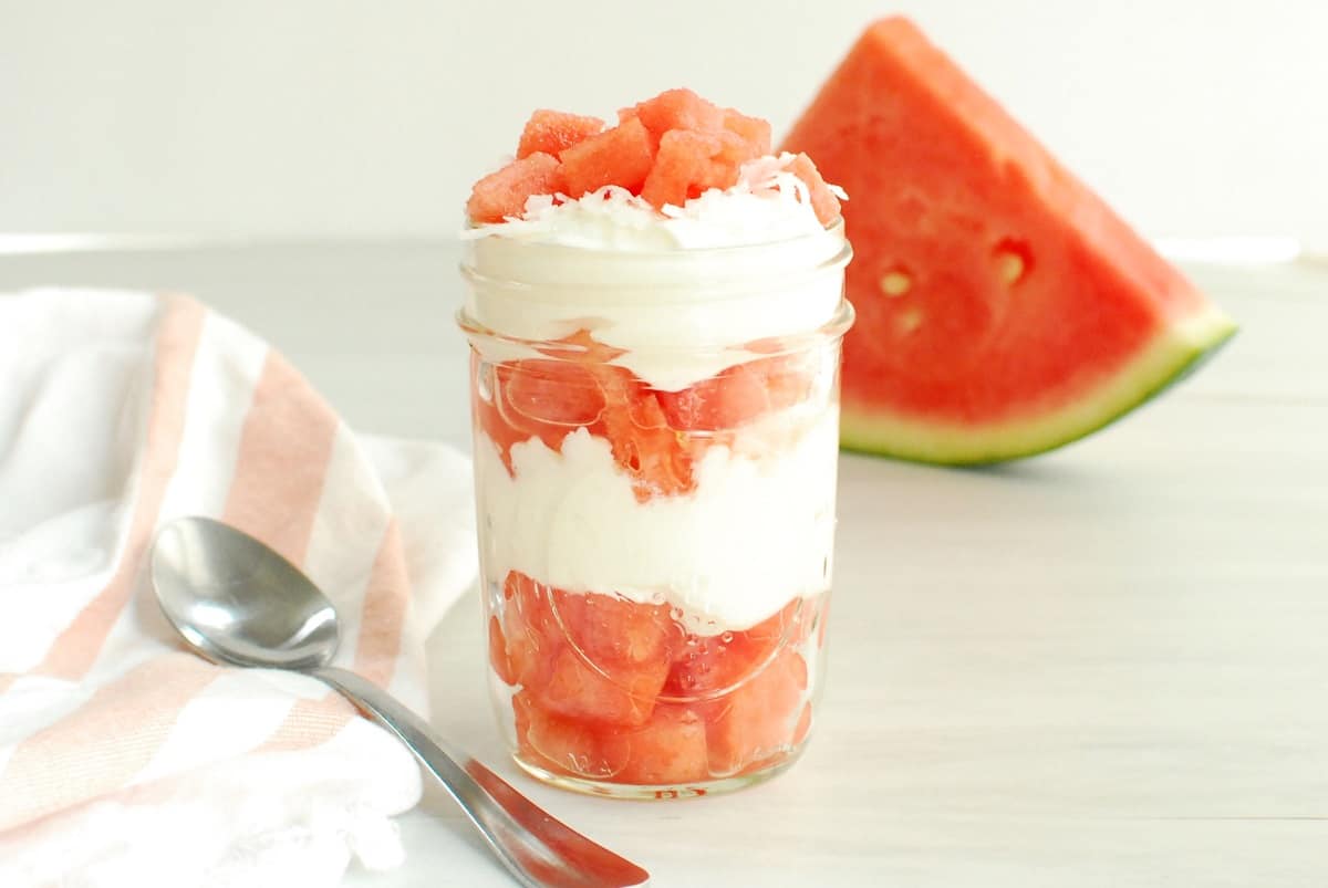 A watermelon and coconut yogurt parfait layered in a mason jar.