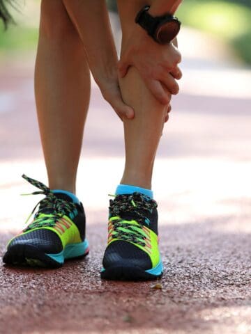 A runner holding her leg in pain due to shin splints.