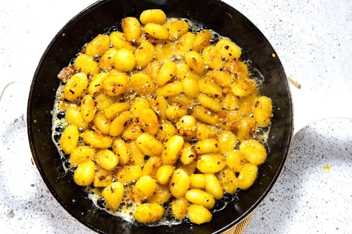 Gnocchi being sauteed with butter, garlic, lemon zest, and crushed red pepper.