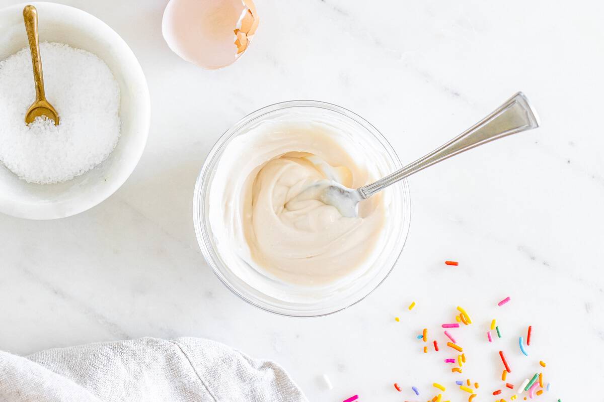 Greek yogurt based frosting in a small bowl with a spoon in it.