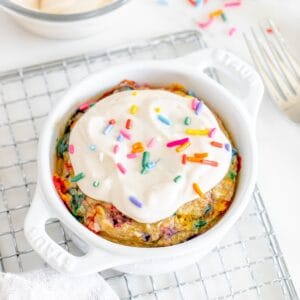 A white ceramic dish with birthday cake baked oats on a cooling rack.