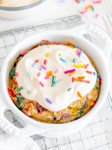 A white ceramic dish with birthday cake baked oats on a cooling rack.