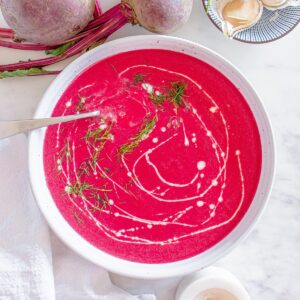 A white ceramic bowl filled with creamy beet soup.
