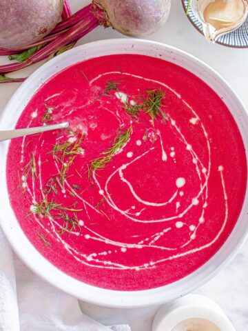 A white ceramic bowl filled with creamy beet soup.