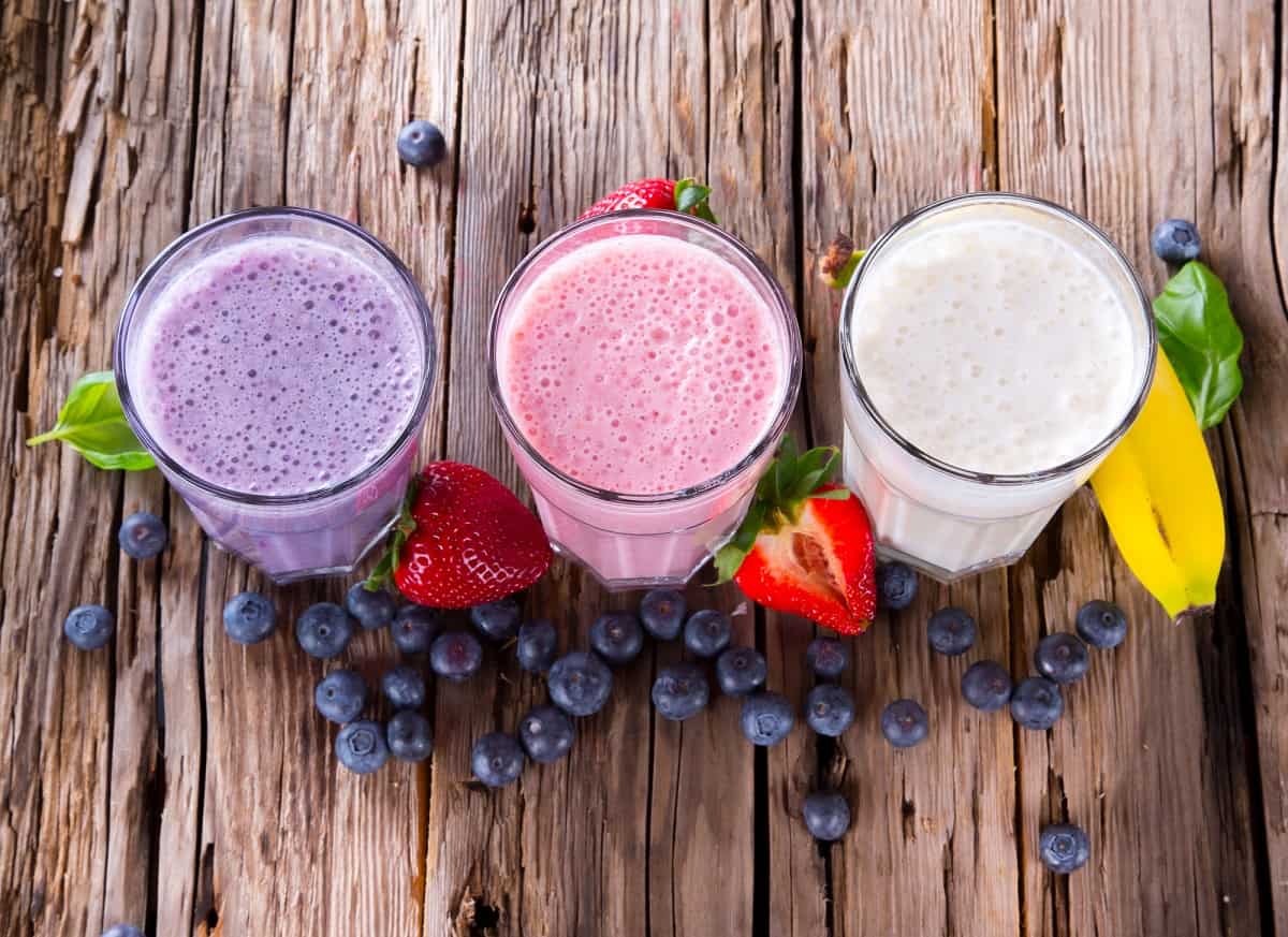 Three homemade post-workout smoothies on a wooden table.