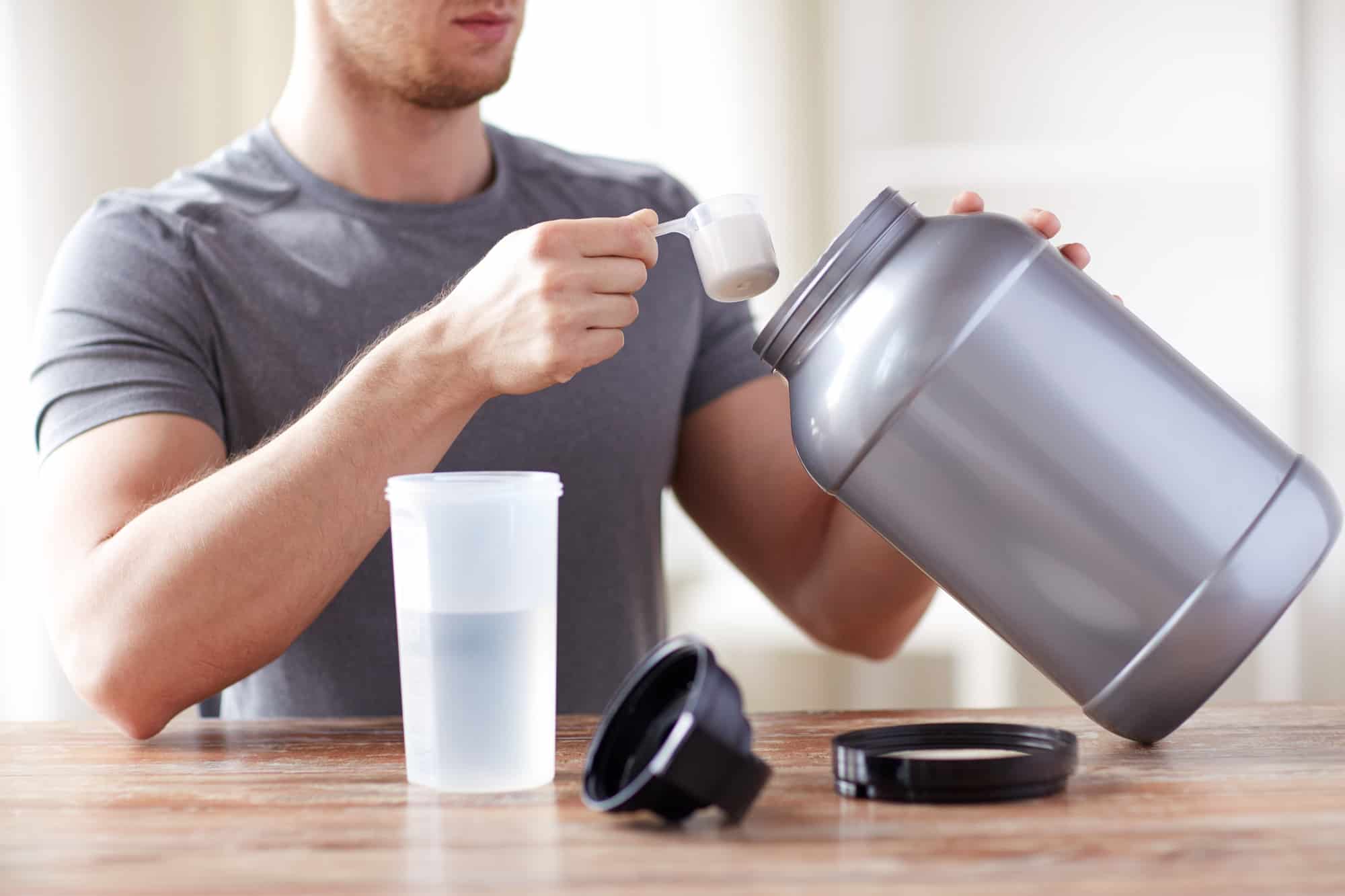 A runner scooping creatine into a reusable water bottle.