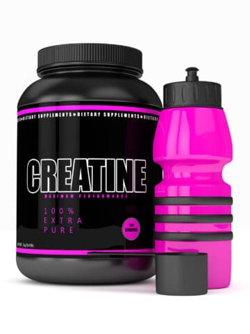 A bottle of creatine next to a water bottle on a white backdrop.