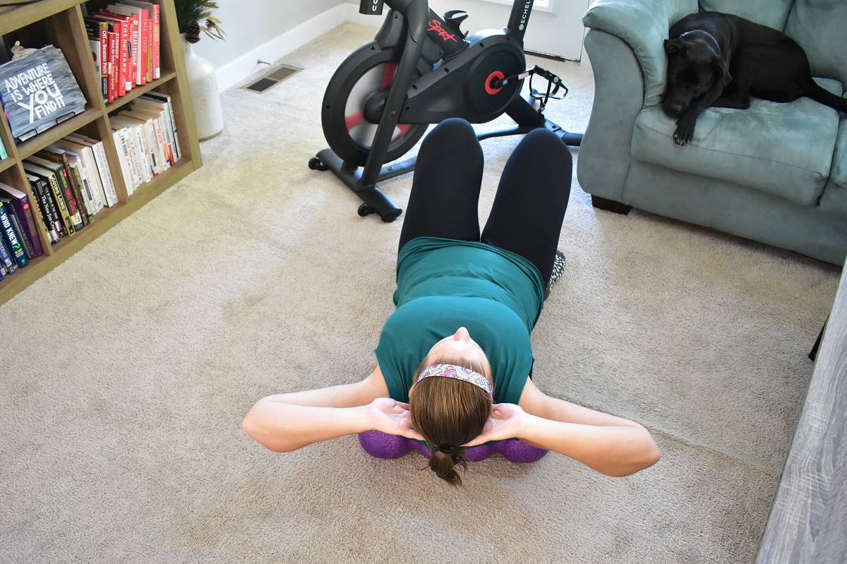 A woman foam rolling her upper back using a Rollga foam roller.