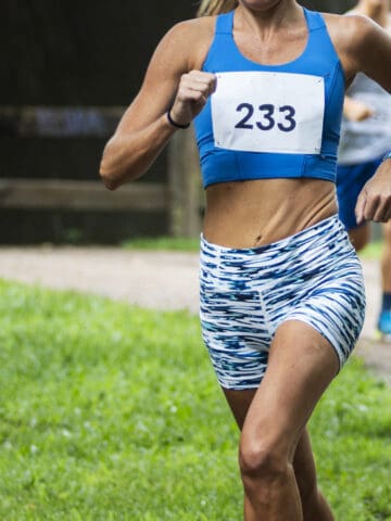 A female runner sprinting at the end of a race to try to achieve a PR.