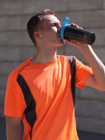 A male runner drinking a pre-workout supplement before going for a run.