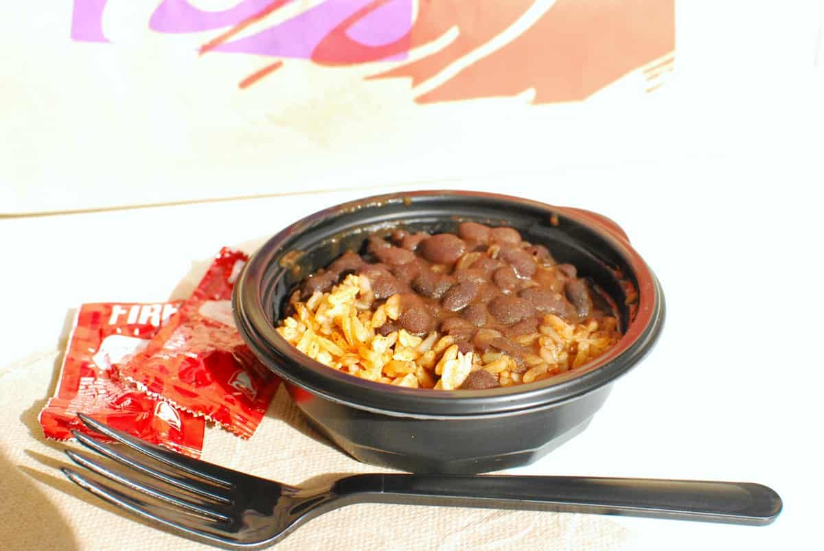 A small bowl of black beans and rice from Taco Bell on a white table.