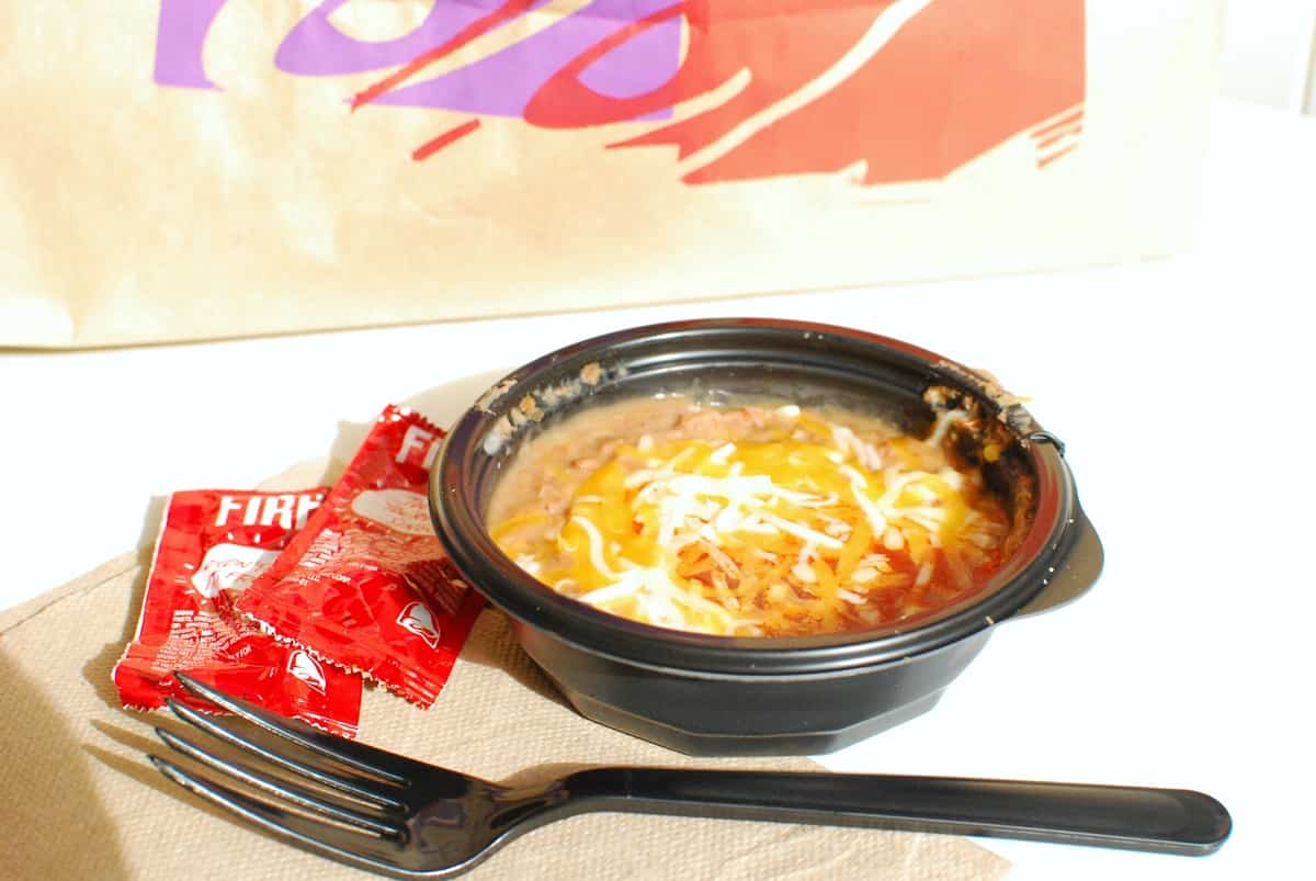 Pintos and cheese from Taco Bell on a white table next to a fork.