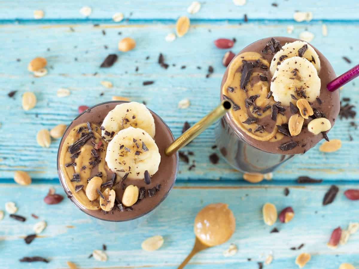 A chocolate banana peanut butter smoothie on a blue table.