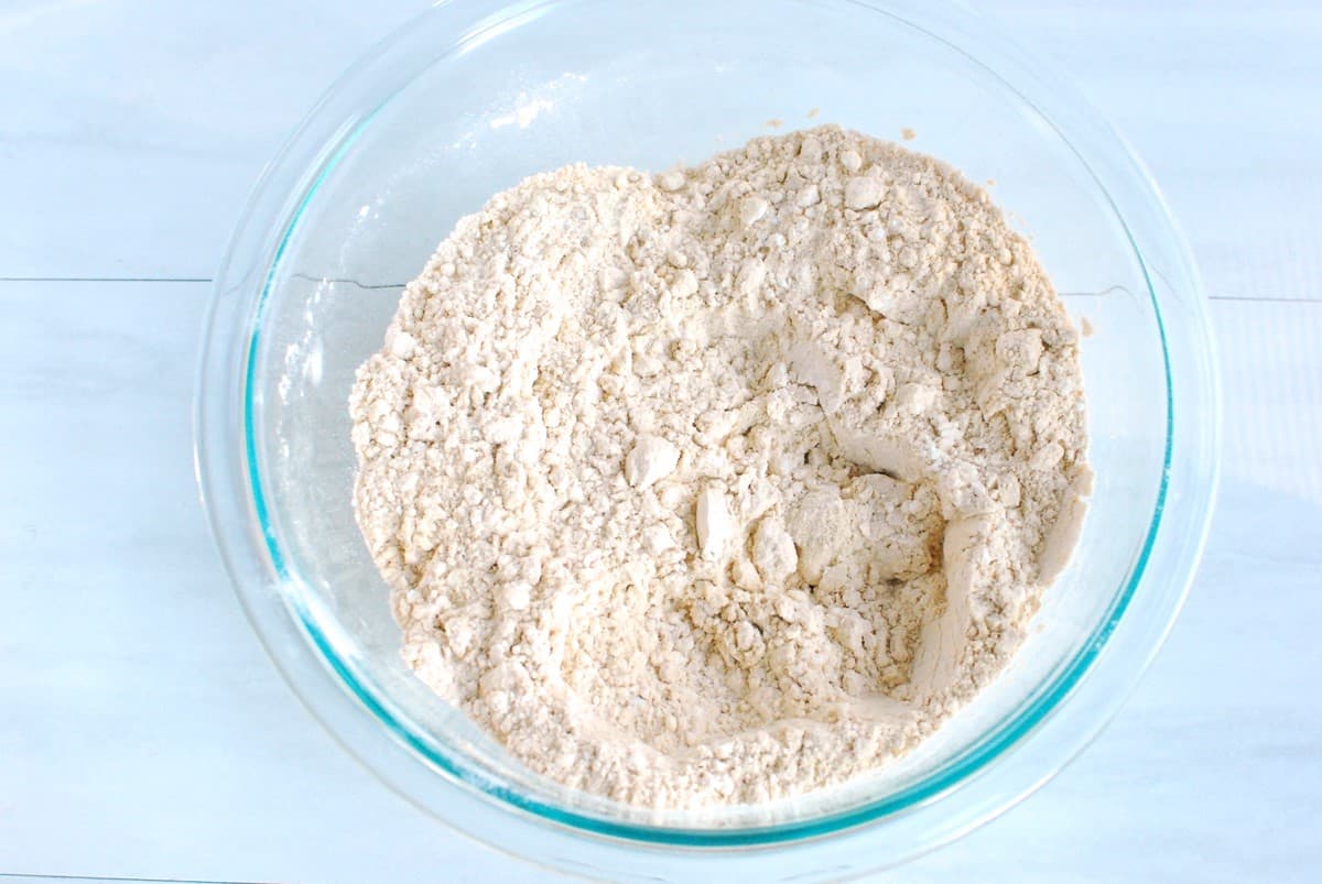 Flour, protein powder, baking soda, and salt mixed together in a glass mixing bowl.