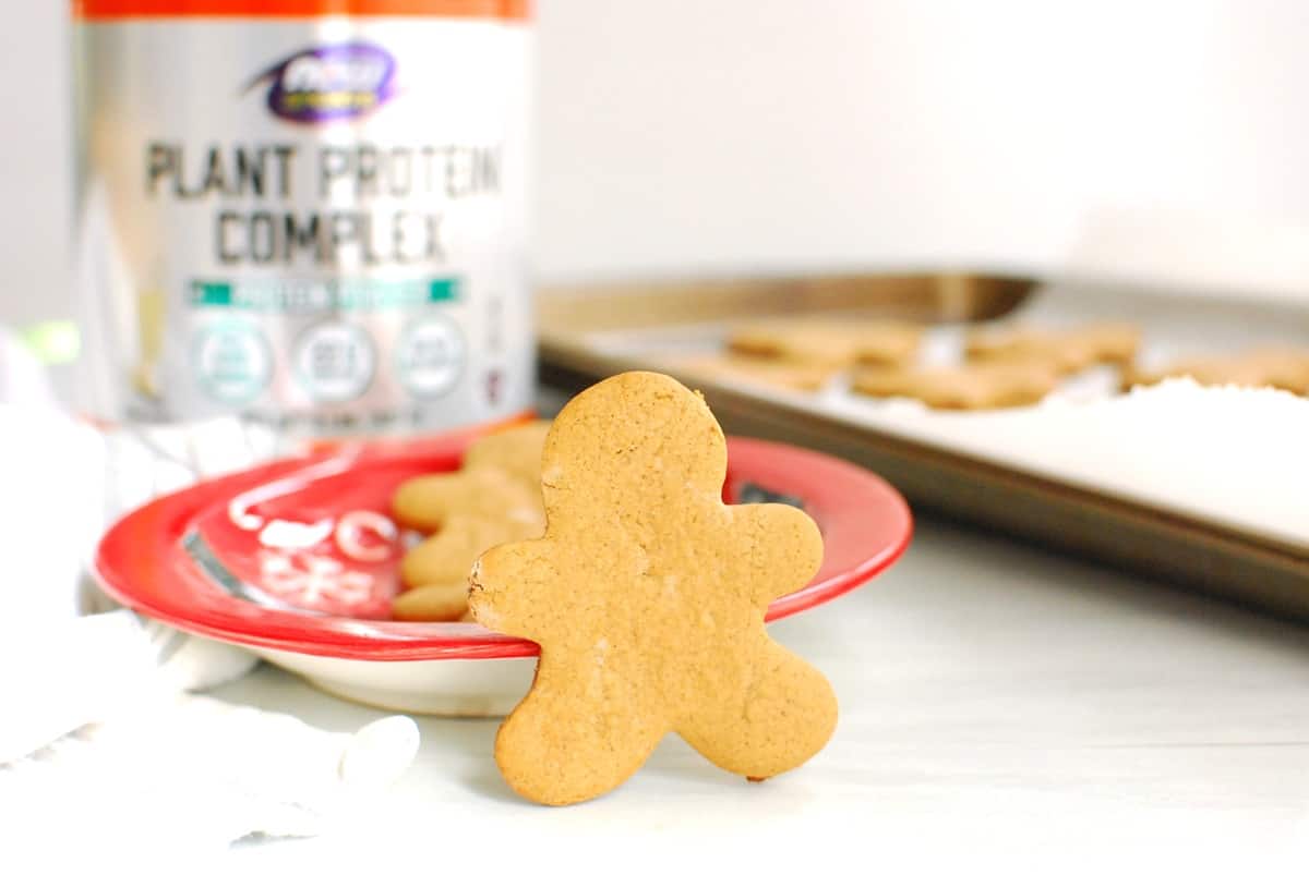 A protein gingerbread man cookie leaning up against a red plate.