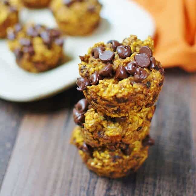 Several pumpkin baked oatmeal cups on a brown table next to a plate and napkin.