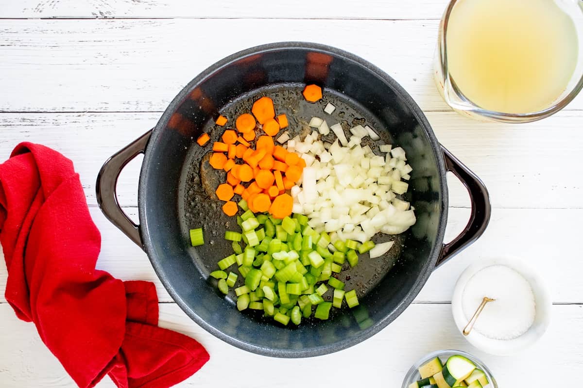 Celery, onions, and carrots being cooked in a pot.