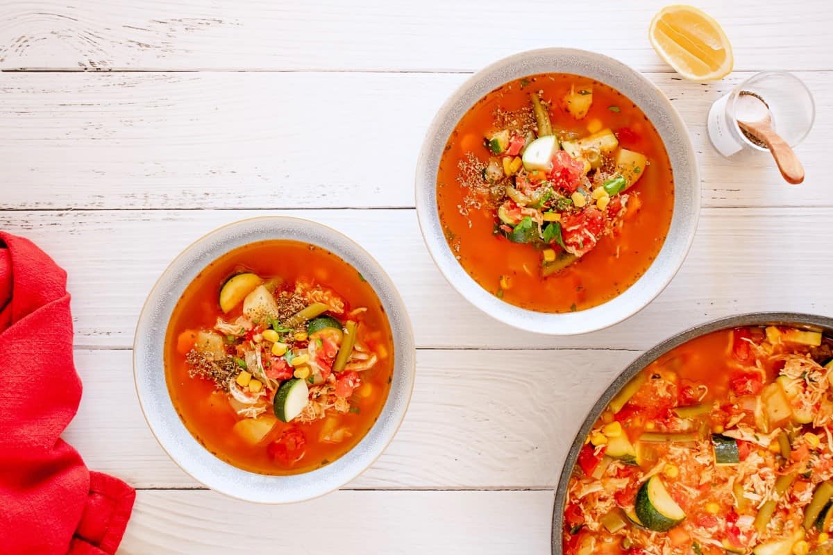 Two white bowls filled with chicken vegetable soup.