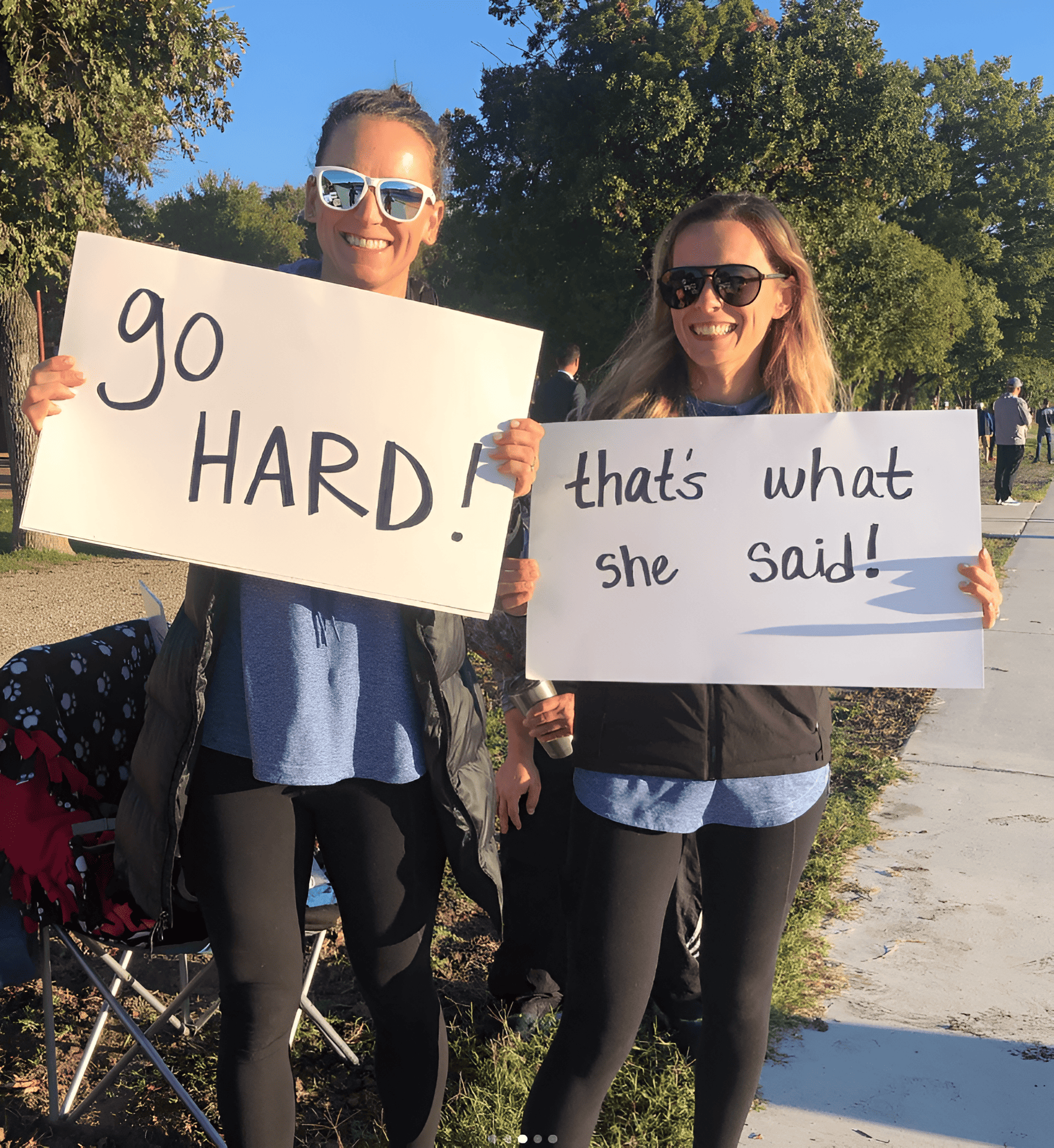 Two women holding a pair of race day signs for a road race.