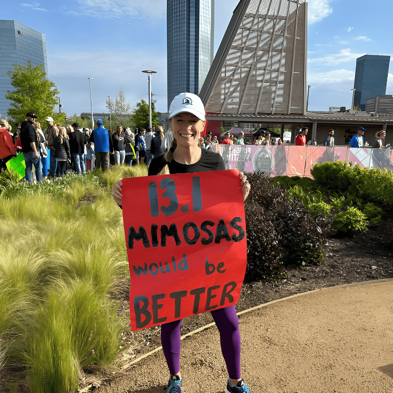 A woman holding a race day sign that says 13.1 mimosas would be better.