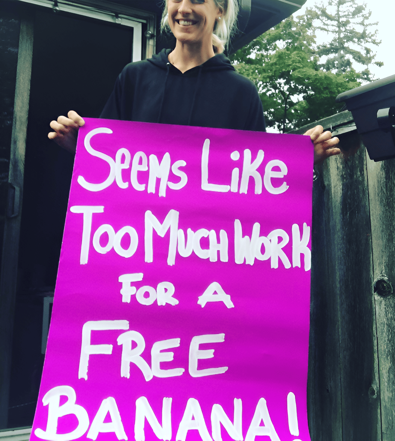 A woman holding a marathon race sign that says seems like too much work for a free banana.