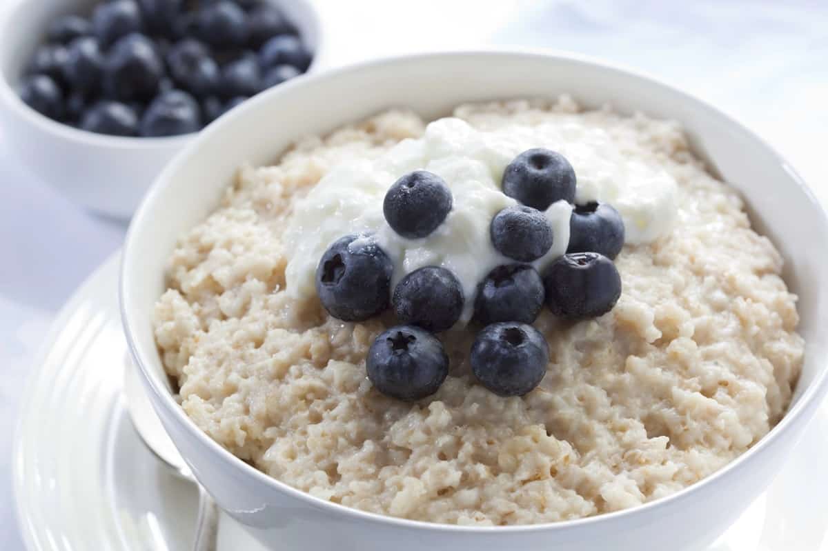 A bowl of oatmeal topped with Greek yogurt and blueberries.