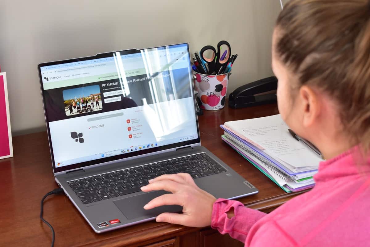 A woman completing the Fit4Mom certification at her desk.