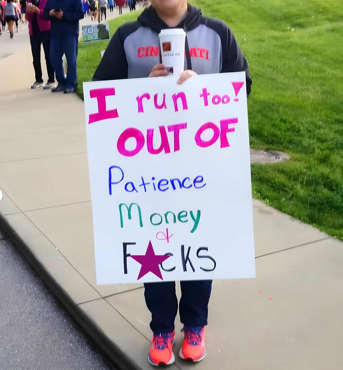 A person holding a funny sign at a race that says "I run too! Out of patience and money".