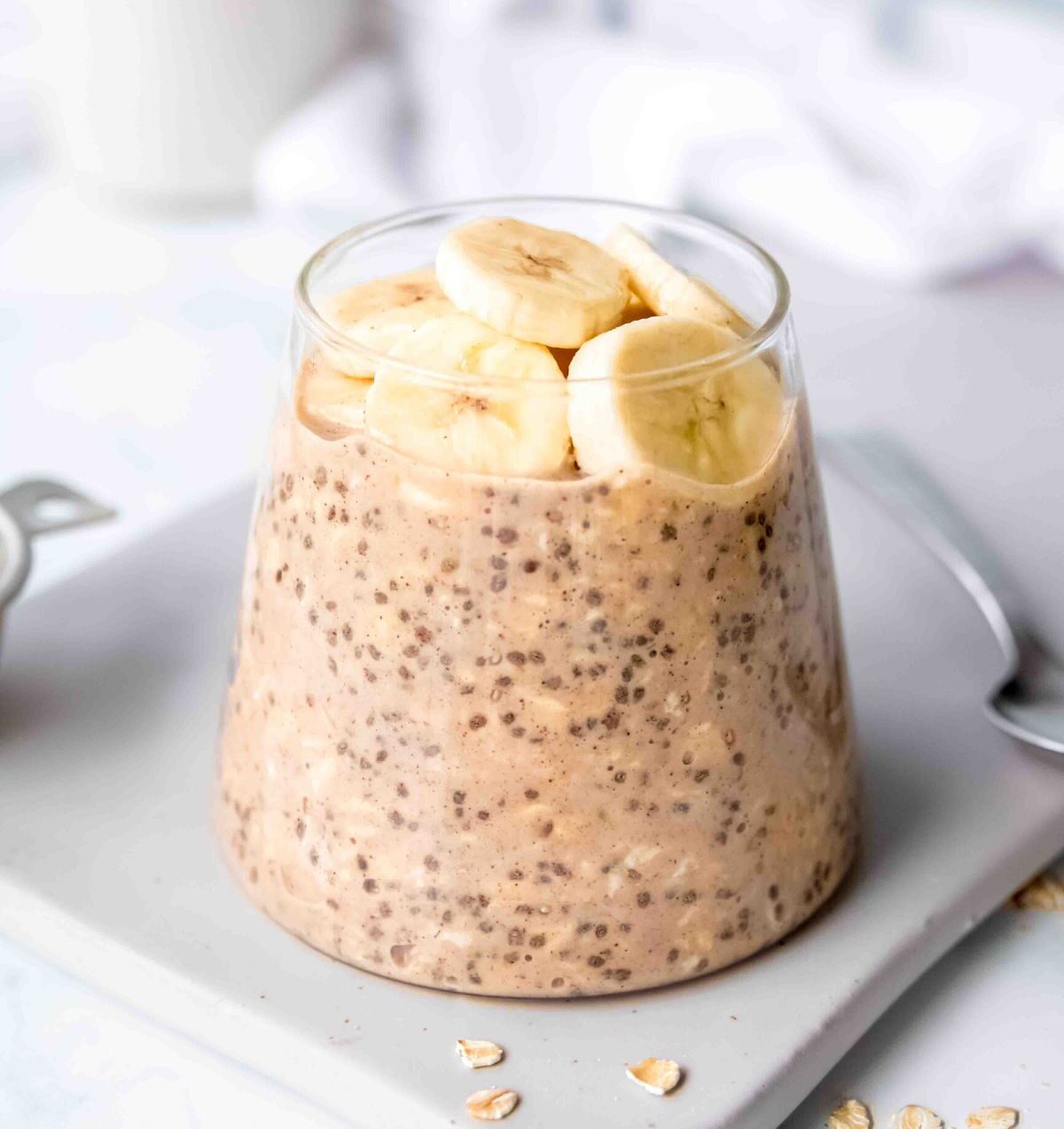A glass cup with peanut butter protein overnight oats that are topped with banana.