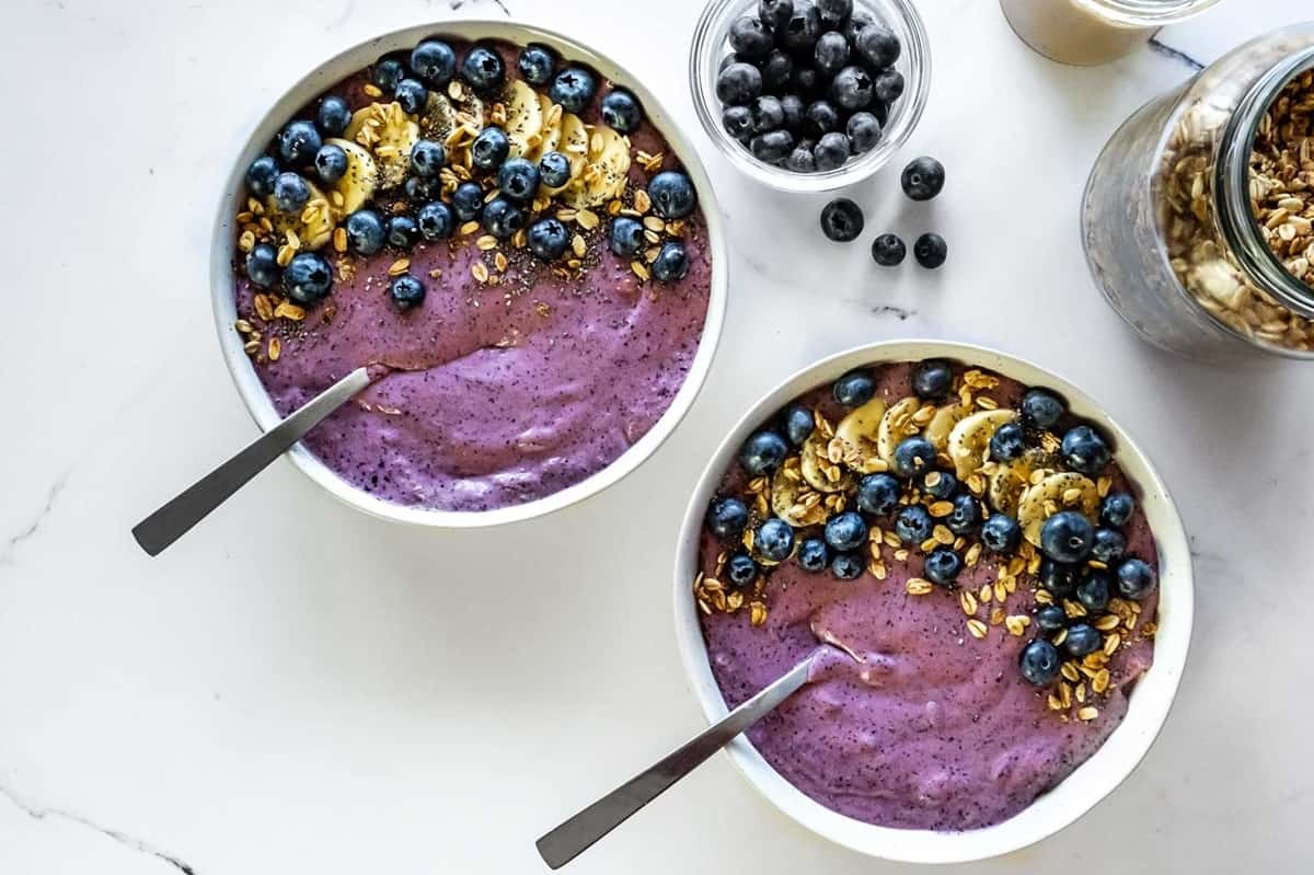 Two blueberry, banana, and mango smoothie bowls.