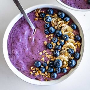 Overhead shot of a blueberry smoothie bowl topped with granola, blueberries, and banana.